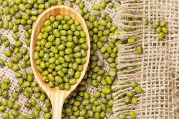 Heap of organic raw green mung bean lentils in wooden spoon