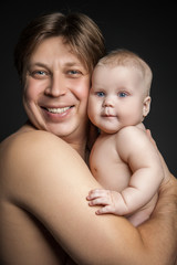 Father holding toddler son both looking at the camera.