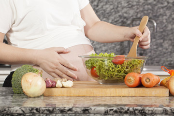 pregnancy cook, a pregnancy tummy woman cooking fresh salad