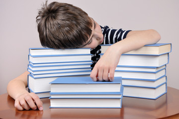 Tired young boy and books