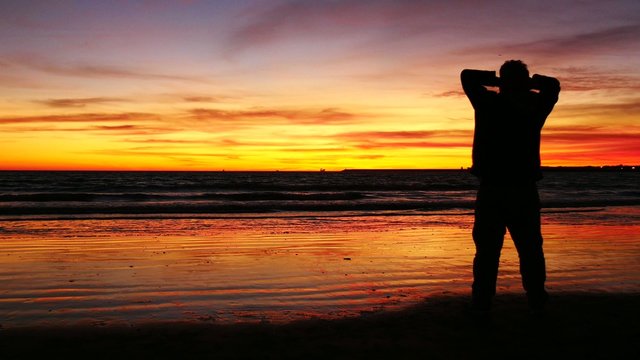 Silhouette of man in front of sunset on the beach (4K)