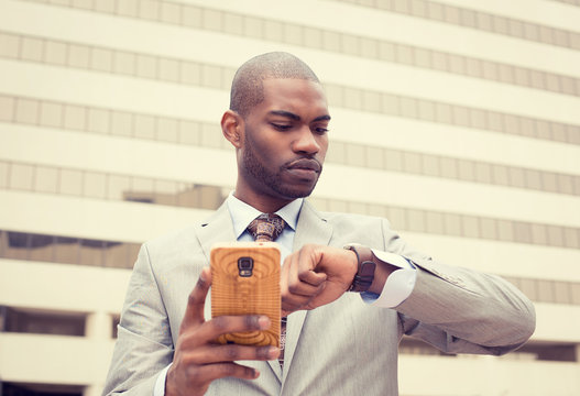 businessman texting on mobile phone and looking at his watch