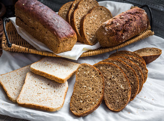 Assorted bread slices in a basket on a white linen tablecloth