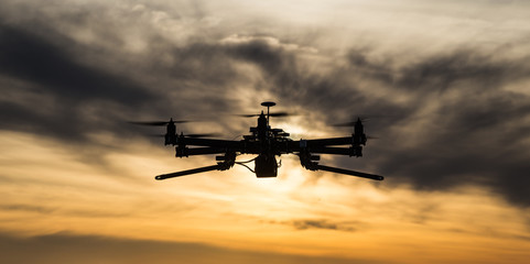 Fototapeta na wymiar Professional drone flying in the sunset with dark clouds