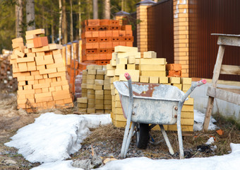 Wheelbarrow and bricks near fence