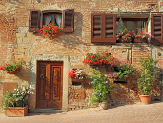 Fototapeta na wymiar beautiful doorway to the tuscan house decorated flowers