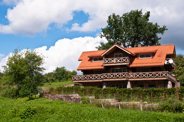 Fototapeta na wymiar Big Wooden Family House with Red Roof Tiles in Nature