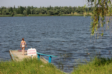 Fototapeta na wymiar Девочка на старом пирсе у озера