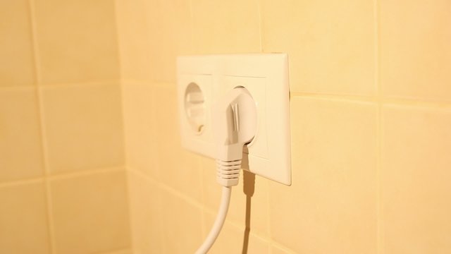 Inserting and pulling an electric plug from a socket on the wall