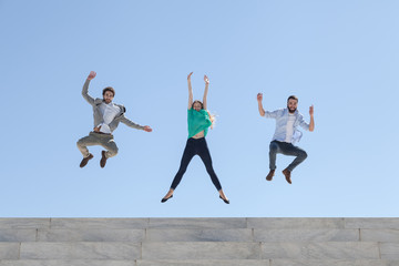 Fototapeta na wymiar Three friends jump on top of a staircase