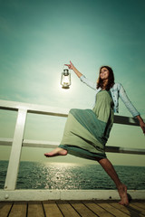 young woman on pier with oil kerosene lamp.