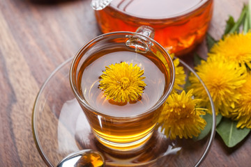 Löwenzahn Tee mit Honig, Blüten und Blättern auf Holztisch