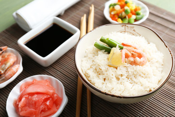 Boiled rice with shrimps and vegetables on bamboo mat background