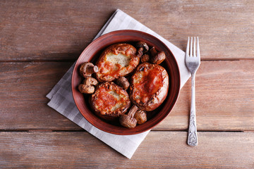 Baked potatoes with mushrooms in bowl on wooden table