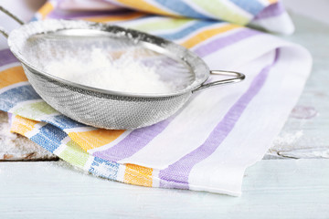 Sifting flour through sieve on wooden table, closeup