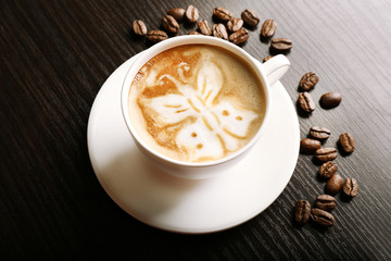 Cup of latte art coffee with grains on wooden background
