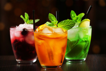 Glasses of cocktails on bar background