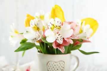 Beautiful flowers in cup, on wooden background