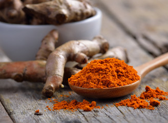 pile of fresh turmeric roots on wooden table