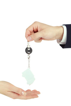 Male hand giving key with trinket to female hand isolated on white