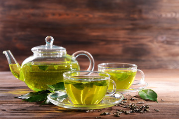 Obraz na płótnie Canvas Cups of green tea on table on wooden background