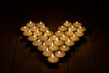 Candles in the shape of heart on old wooden background