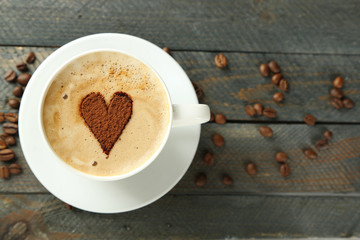 Cup of cappuccino with heart of cocoa on wooden table