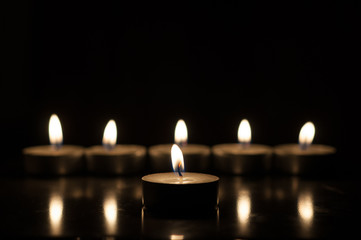 One candle and group of candles on old wooden background