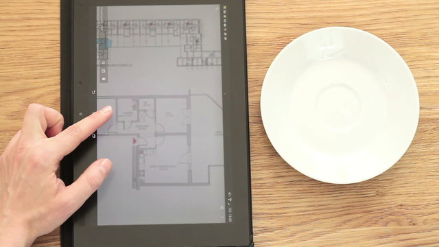 Female architect analyzing blueprint on digital tablet
