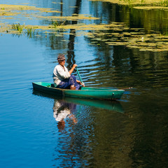 Elderly Man Fishing On River Boat