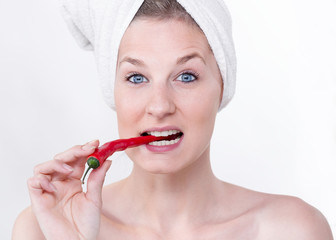 Junge Frau mit einer Chilischote im Mund