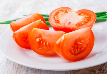 sliced tomato and chives on a white plate