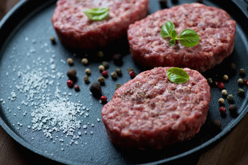 Close-up of raw beef cutlets with different spices, shallow DOF