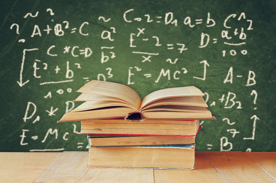  Image of school books on wooden desk over green background with
