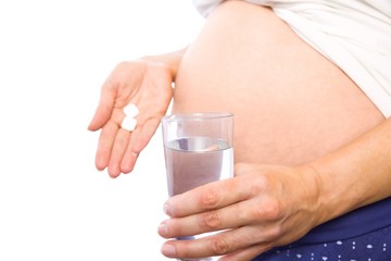 Pregnant woman taking a vitamin tablet