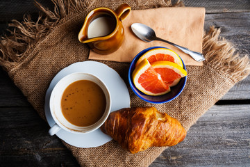 Cup of coffee with milk, grapefruit and fresh croissant