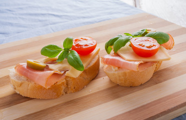 Small sandwiches with smoked ham, cheese and cherry tomato