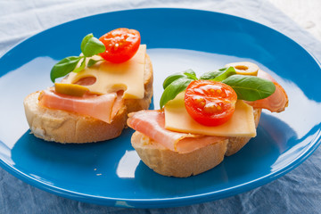 Small sandwiches with smoked ham, cheese and cherry tomato
