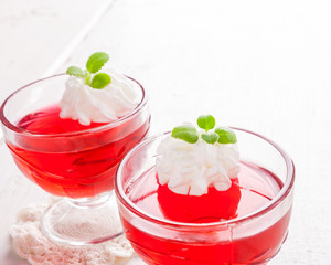 Red jelly with whipped cream in a glass bowl