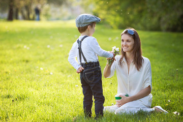 Beautful kid and mom in spring park, flower and present. Mothers
