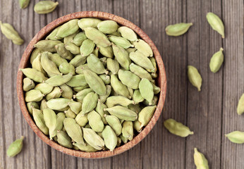 Green cardamom ayurveda plant spice in a wooden bowl on vintage