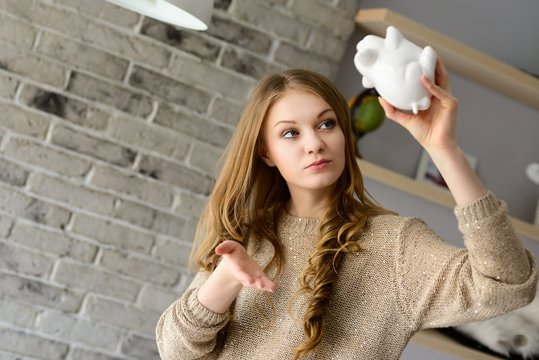 Woman trying to find more money in the piggy bank