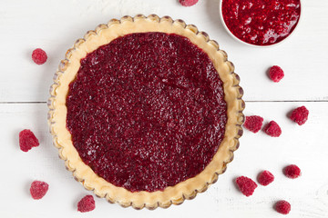 Homemade raspberry pie preparation. Tart with berry jam on white