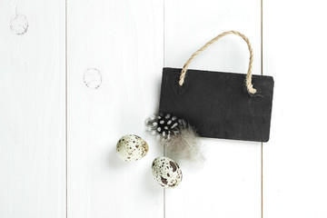 Quail eggs and feather with vintage blackboard on white wooden b