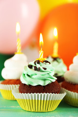 Delicious birthday cupcakes on table on bright background