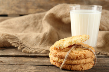 Tasty cookies and glass of milk on rustic wooden background