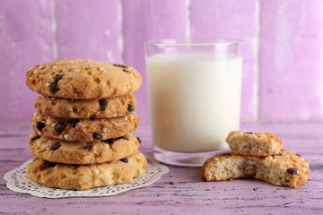 Tasty cookies and glass of milk on color wooden background