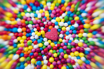 Fototapeta na wymiar Macro of Sugar Heart over colorfull balls powder background