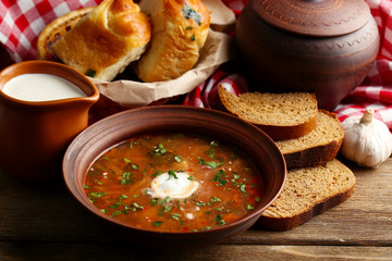 Ukrainian beetroot soup - borscht in bowl and pot, on napkin, on wooden background