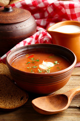 Ukrainian beetroot soup - borscht in bowl and pot, on napkin, on wooden background